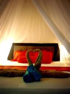 Un dormitorio con una cama con un animal de peluche en forma de corazón en Yayan Bungalow, en Gili Air