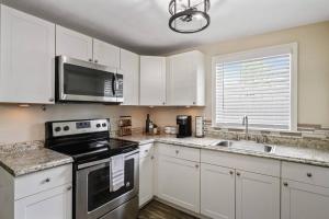 a kitchen with white cabinets and a black stove top oven at The Spanish Beach Home only 10mins from the beach! in Largo