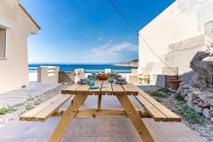a wooden picnic table on a patio with a view of the ocean at LA MARONAISE - Maison dans la calanque in Marseille