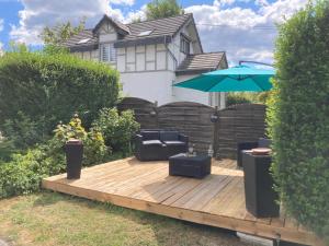 a wooden deck with a couch and an umbrella at My house in Spa