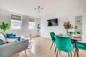 ein Wohnzimmer mit einem Tisch und grünen Stühlen in der Unterkunft Modern 2 Bed Apartment in Central London, Kensington in London