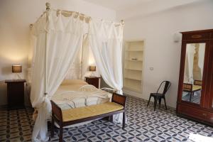 sypialnia z łóżkiem z baldachimem i krzesłem w obiekcie Charme in centro - Tourist rental w mieście Agrigento
