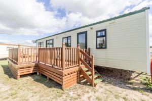 uma casa móvel com um grande deque de madeira em Great Dog Friendly Caravan For Hire At North Denes In Suffolk Ref 40068nd em Lowestoft