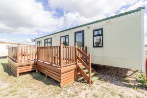 a mobile home with a large wooden deck at Great Dog Friendly Caravan For Hire At North Denes In Suffolk Ref 40068nd in Lowestoft