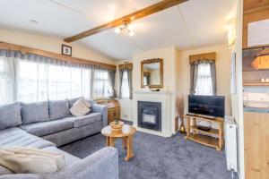 a living room with a couch and a television at Great Dog Friendly Caravan For Hire At North Denes In Suffolk Ref 40068nd in Lowestoft