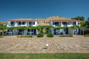 a large white house with a large yard at Sunset Hotel in Agios Ioannis Kaspaka