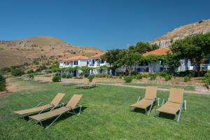 a group of lawn chairs sitting in the grass at Sunset Hotel in Agios Ioannis Kaspaka