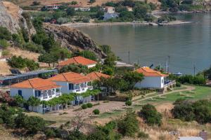 a row of houses on a hill next to the water at Sunset Hotel in Agios Ioannis Kaspaka