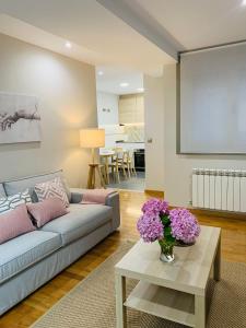 a living room with a couch and a table with flowers at Apartamento Pereiro Viveiro in Viveiro