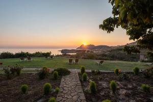 a sunset over a field with tables and chairs at Sunset Hotel in Agios Ioannis Kaspaka