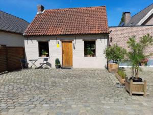 Casa blanca con puerta amarilla y patio en Vakantiehuisje 't Morehof, en Oosterzele
