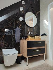 uma casa de banho com um WC, um lavatório e um espelho. em Latarnik - luksusowe apartamenty w Stilo em Osetnik