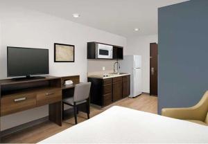 a room with a desk with a television and a kitchen at WoodSpring Suites Littleton-South Denver in Littleton