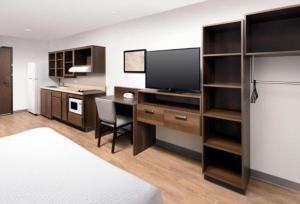 a bedroom with a desk with a television and a bed at WoodSpring Suites Littleton-South Denver in Littleton