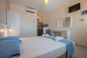 a bedroom with a large white bed with blue pillows at Sunset Hotel in Agios Ioannis Kaspaka