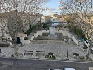 a park with a monument and benches and trees at La pergola in Valros