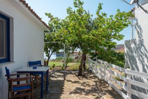 a table and chairs next to a fence with a tree at Sunset Hotel in Agios Ioannis Kaspaka
