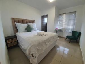 a bedroom with a bed and a green chair at BF Dlamini Guest House in Amanzimtoti