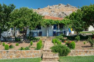 a house with a garden in front of a mountain at Sunset Hotel in Agios Ioannis Kaspaka