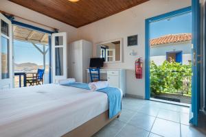 a bedroom with a bed and a large window at Sunset Hotel in Agios Ioannis Kaspaka