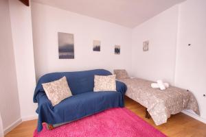 - un salon avec un canapé bleu et un lit dans l'établissement CUENCALOFT RAMÓN Y CAJAL 18, à Cuenca