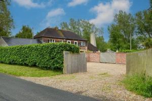 a fence in front of a house with a hedge at The Hideaway @ Flagham Cottage. in Malmesbury
