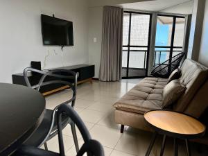 uma sala de estar com um sofá e uma televisão em Edf Casabela - Apartamento Beira Mar com 2 quartos sendo 1 suíte com vista para as piscinais naturais com ar condicionado em todos os quartos e na sala - 1 vaga de garagem em Maceió