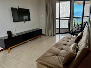 sala de estar con sofá y TV de pantalla plana en Edf Casabela - Apartamento Beira Mar com 2 quartos sendo 1 suíte com vista para as piscinais naturais com ar condicionado em todos os quartos e na sala - 1 vaga de garagem en Maceió