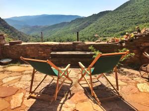 dos sillas sentadas en la parte superior de una pared de piedra en Casa Manel - Loft rústico con encanto, en Montcortès