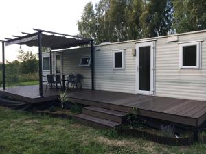 a mobile home with a deck and a table at Holender nad Saskiem in Kobyłocha