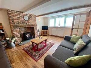 a living room with a couch and a fireplace at Guernsey Cottage in Ottery Saint Mary