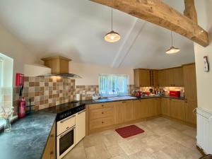 a large kitchen with wooden cabinets and black appliances at Guernsey Cottage in Ottery Saint Mary