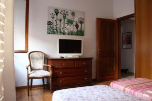- une chambre avec une télévision sur une commode et une chaise dans l'établissement Casa Pamphili, à Rome