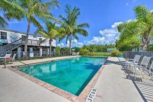 a swimming pool with chairs and palm trees at Everglades City Cabin Dock and Heated Pool! in Everglades City