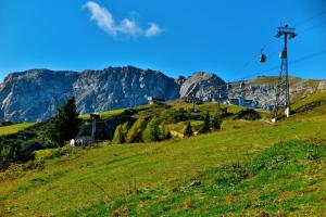 a grassy hill with a ski lift in front of a mountain at Appartements Nassfeld LUX in Sonnenalpe Nassfeld