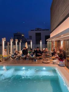 un grupo de personas sentadas alrededor de una mesa junto a una piscina en Three O Nine Hotel, en Beirut