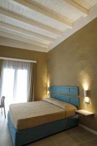 una camera da letto con letto con testiera blu e finestra di Palazzo Mancina a Trapani
