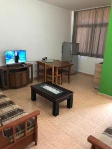 a living room with a table and a tv at Sunnyside Apartments in Hamallë +13 photos