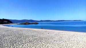 - une plage avec des personnes se promenant sur le sable et l'eau dans l'établissement Hotel Baixamar, à Sanxenxo