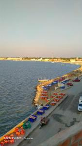 einen Strand mit Stühlen und Sonnenschirmen und dem Wasser in der Unterkunft شقق وشليهات رشيد علي ضفاف بحيره قارون in Shakshuk