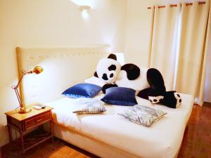 a bed with a panda bear and pillows on it at The Blue Bamboo Hotel - Duna Parque Group - "Ex Casa dos Arcos" in Vila Nova de Milfontes