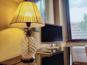 una lampada su un tavolo con monitor per computer e ananas di CASA DUCHESSE al Castello a Ferrara
