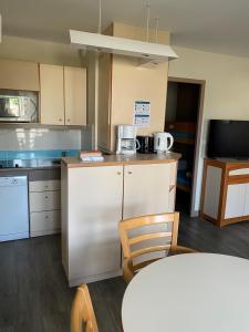 a kitchen with a white refrigerator and a table at Résidence Pierre & Vacances Ty Mat in Saint Malo