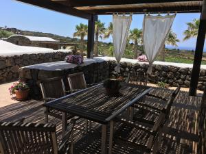 a patio with a table and chairs and a stone wall at Residenza delle Palme in Pantelleria