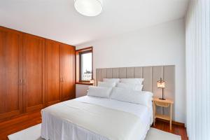 a bedroom with a large white bed and wooden cabinets at Leça Front Beach Luxury Penthouse in Leça da Palmeira