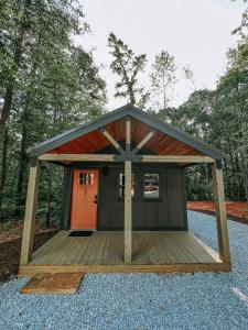 a small cabin with a roof and a wooden porch at Cabin 5 One Bedroom W Kitchen in Hartwell