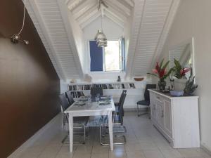 una sala da pranzo con tavolo e sedie bianchi di L'Arbre aux Papillons, Marina de Rivières-Sens a Gourbeyre