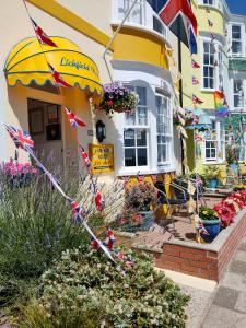 ein gelbes und weißes Haus mit einem Regenschirm und Blumen in der Unterkunft Lichfield House in Weymouth