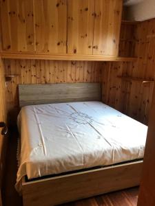 a bed in a room with wooden walls and cabinets at Finestra sull’Adamello in Passo del Tonale