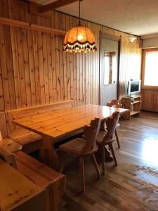 een houten eetkamer met een grote houten tafel en stoelen bij Finestra sull’Adamello in Passo del Tonale